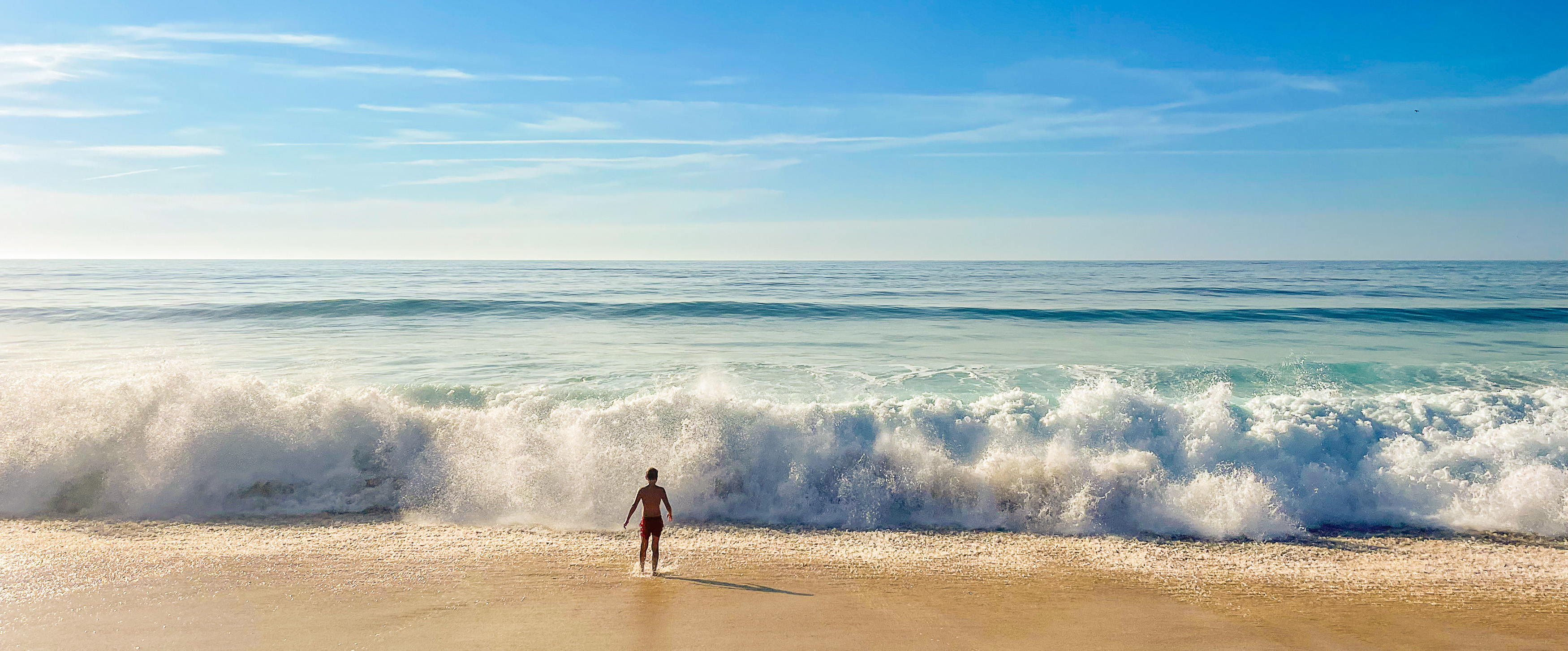 Ein Surfer mit Brett am weiten Strand von Carvalhal.