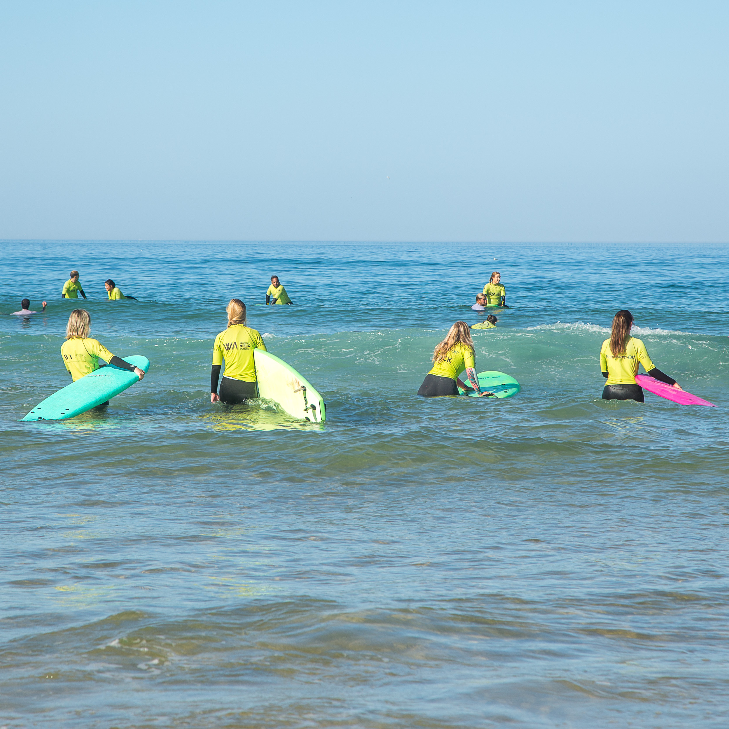 Eine Gruppe von Reitern am weiten Sandstrand von Comporta im Sommerlicht.