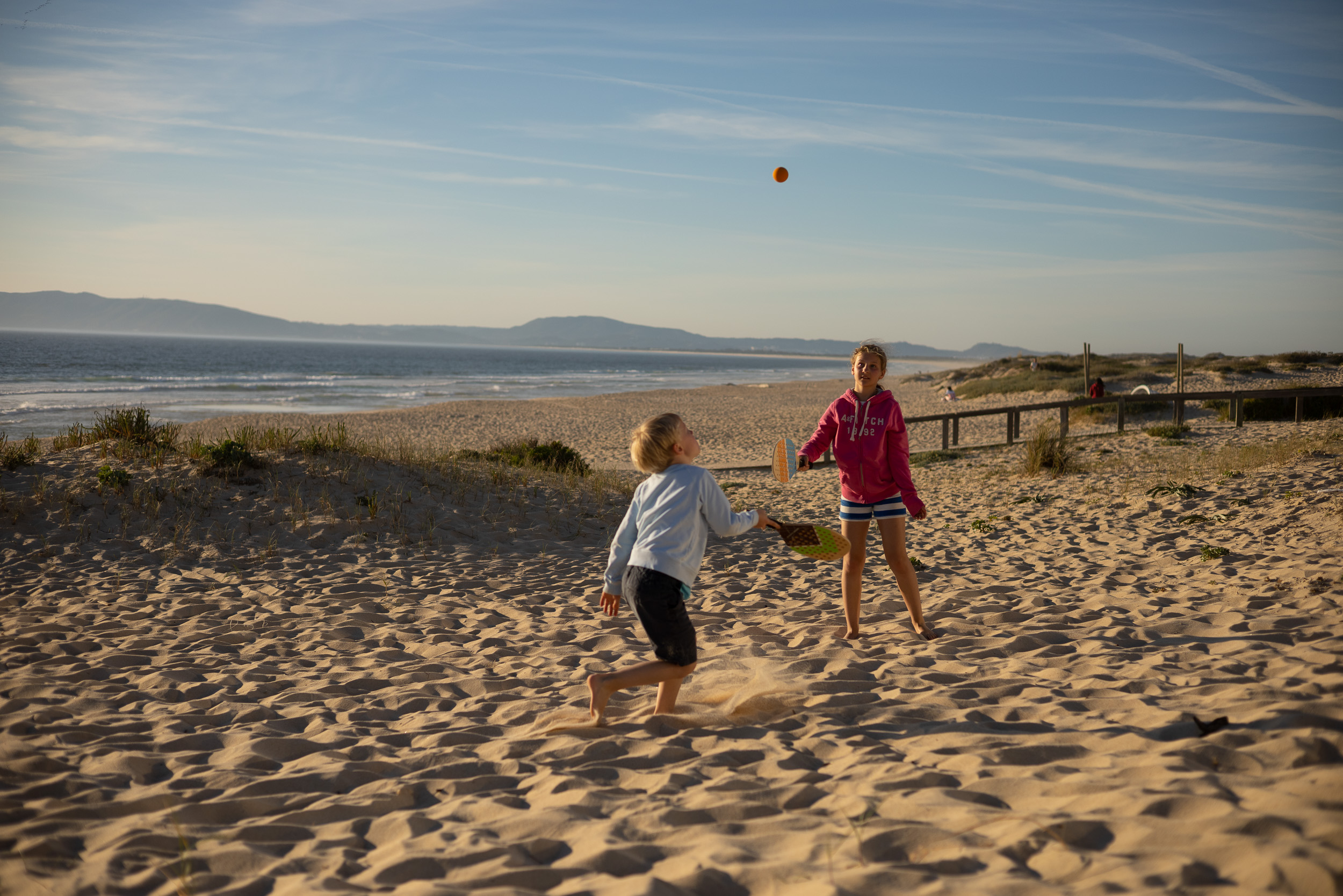 Zwei Kinder spielen am späten Nachmittag Frescobol am Sandstrand von Comporta.