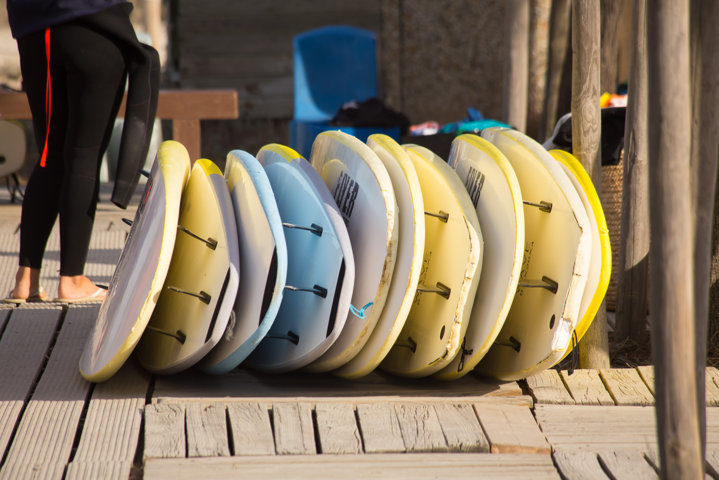 De grandes planches de surf sont soigneusement alignées contre une cabane de surf en bois.